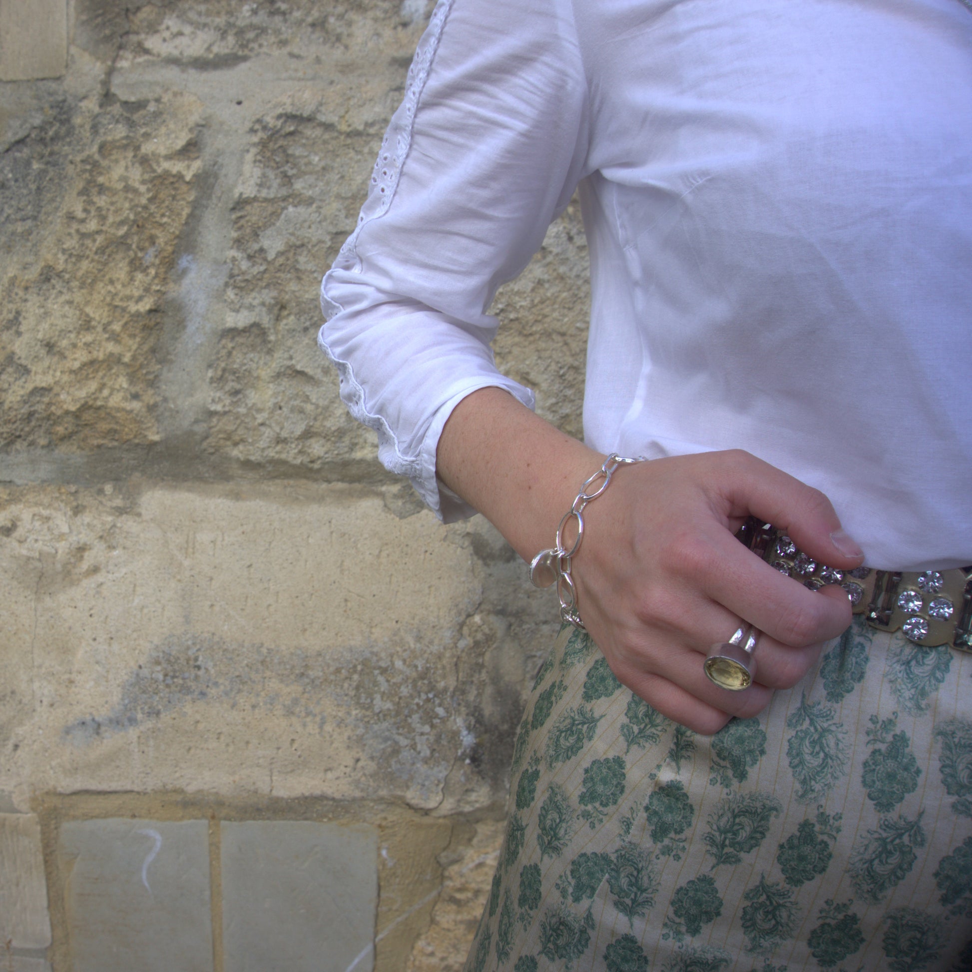 Madeleine wearing the citrine and silver cocktail ring on her middle finger, while wearing a green silk skirt and white top.