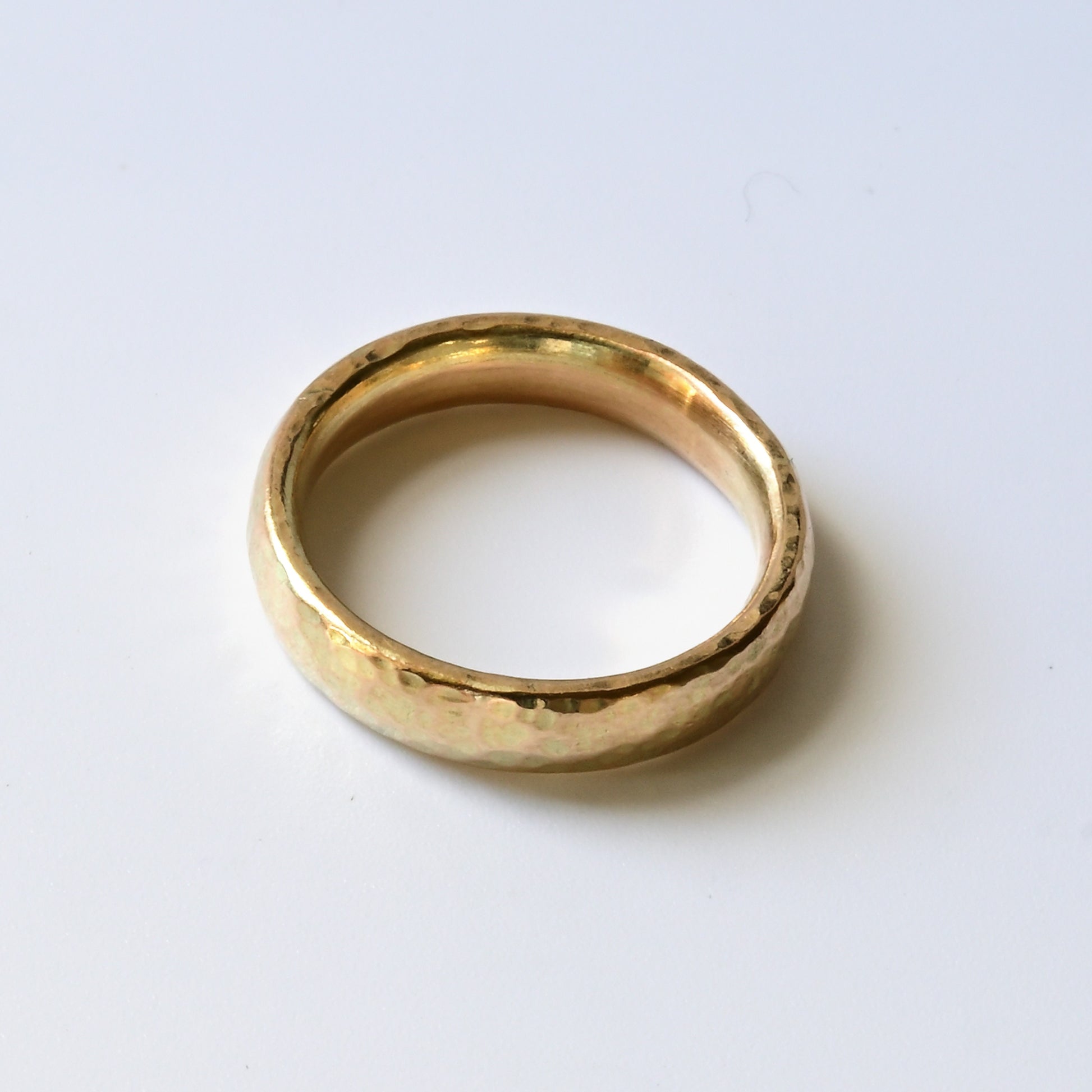 birds eye view of simple 9ct yellow wedding ring on a bright white background.