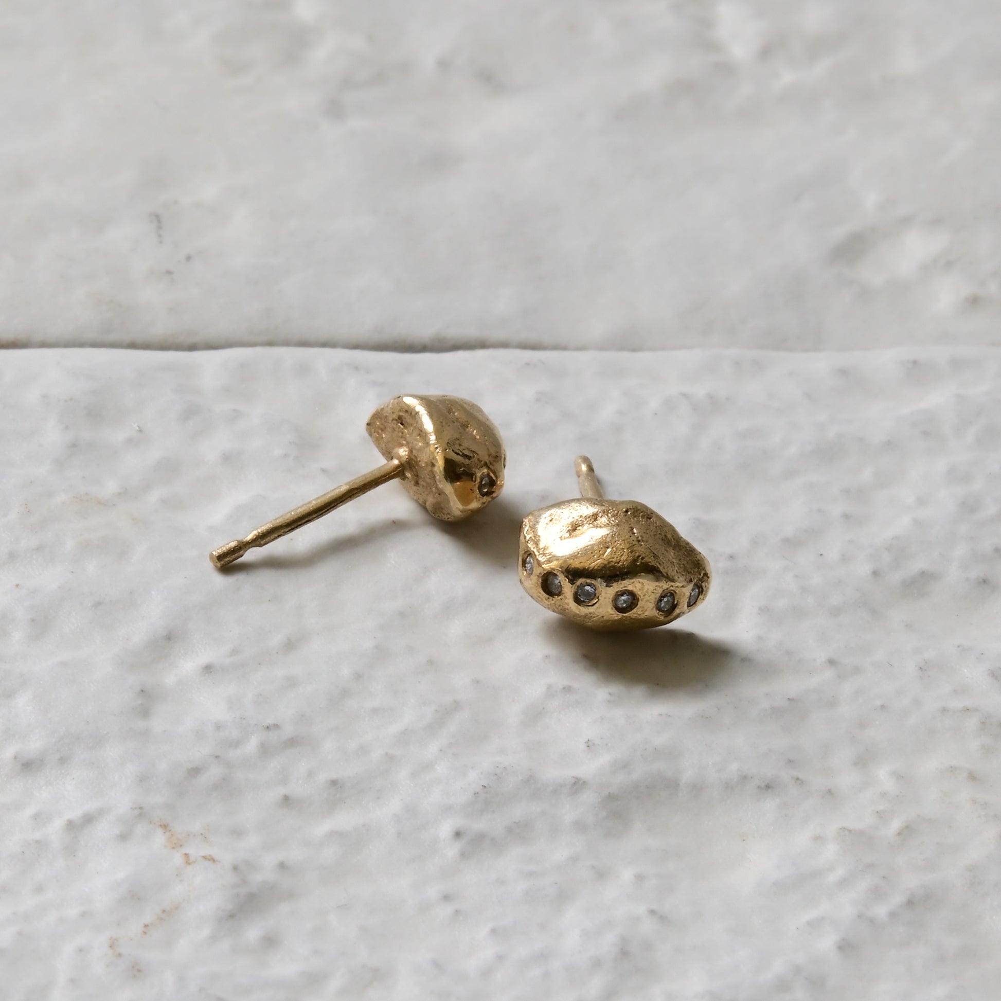 diamond gold studs pictured on white brick in the Cotswold's, handmade fine jewellery by Madeleine.