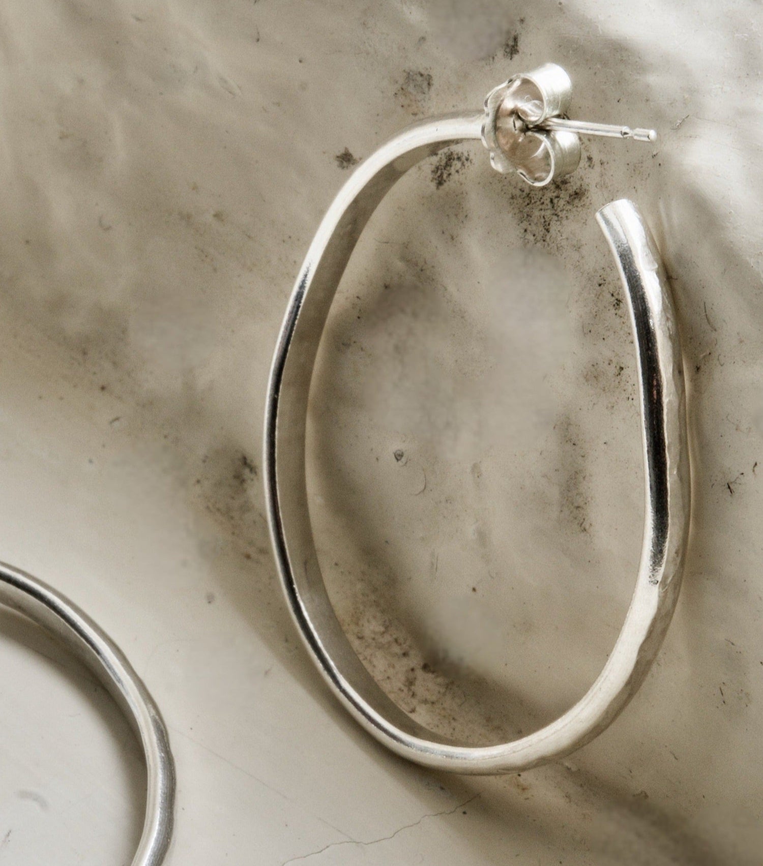 Classic silver hoop photographed on a rustic white Cotswold stone background.