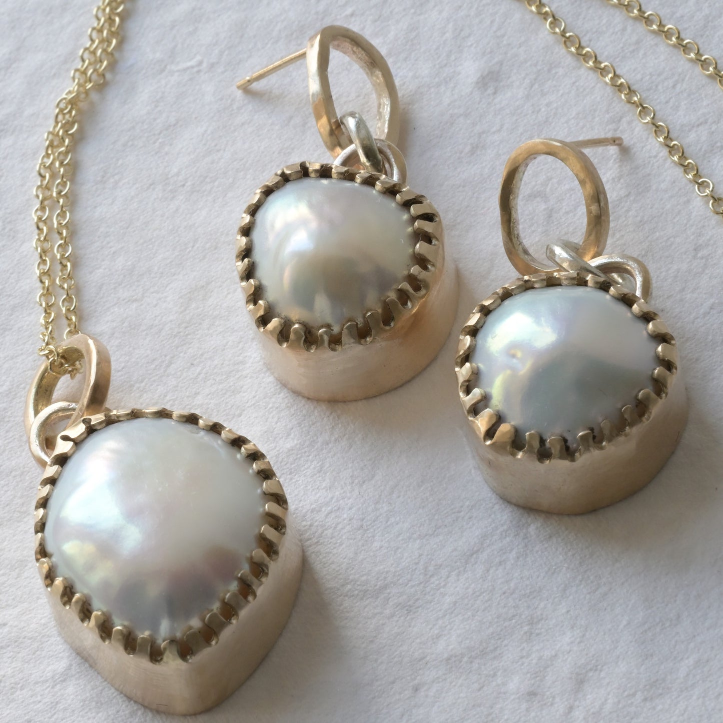 Pair of baroque pearl earrings and baroque pearl necklace picture together on white.