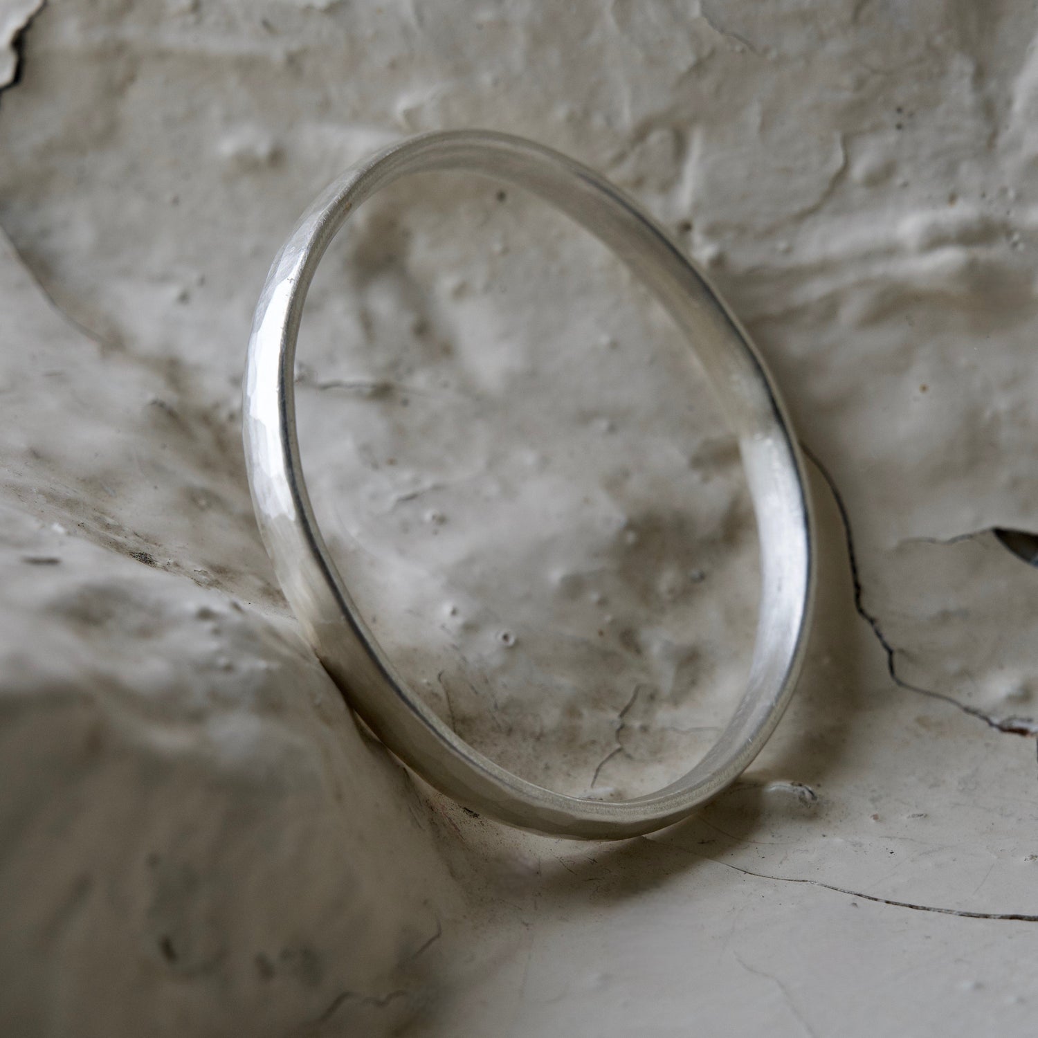 Chunky silver bangle photographed on Cotswold white brick.