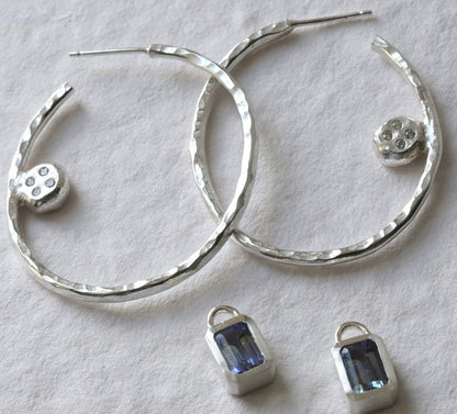 A pair of tanzanite and sterling silver hoops with diamond photographed on white. Handmade fine jewellery by Madeleine.