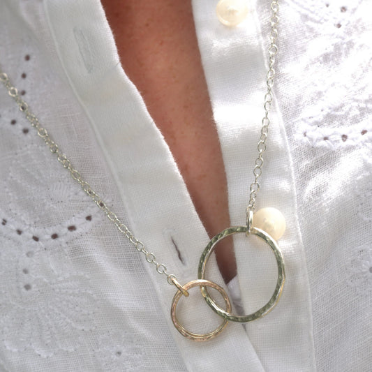 Madeleine wearing the silver and gold circles necklace with a white shirt.