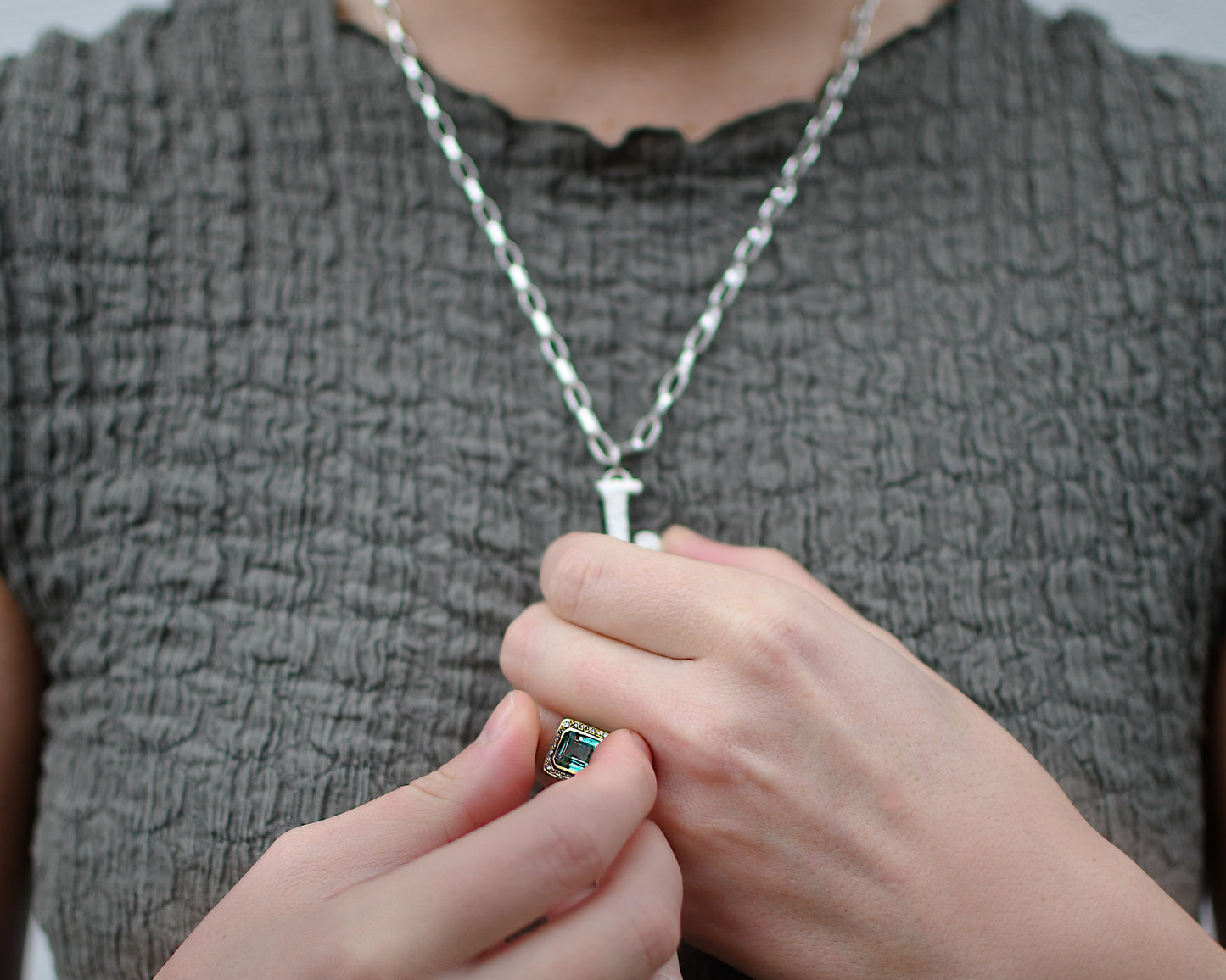 Maddy wearing a tourmaline ring and silver diamond letter pendadnt.